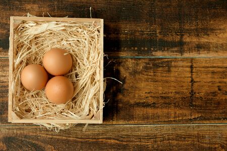 Eggs on straw placed on a wooden tableの写真素材