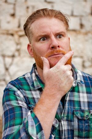 Portrait of red haired hipster man with blue plaid shirt expressing a emotionの写真素材