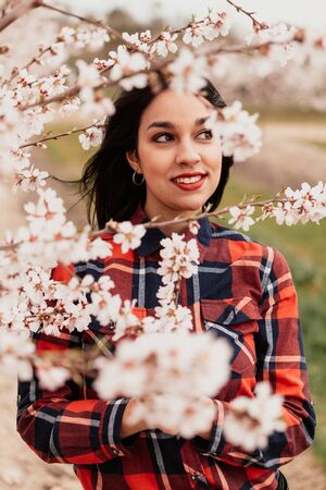 Brunette girl near a almond tree with many flowersの写真素材