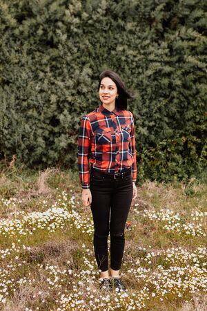Pretty brunette girl with red plaid shirt in the park