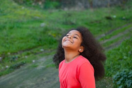 Pretty girl with long afro hair in the garden with a blue coatの写真素材