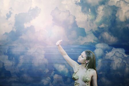 Beautiful girl among the clouds looking towards the lightの写真素材