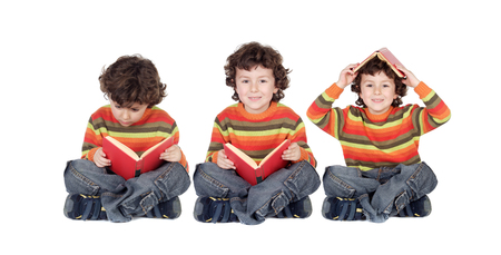 Three equal children reading a red book seated isolated on a white backgroundの写真素材
