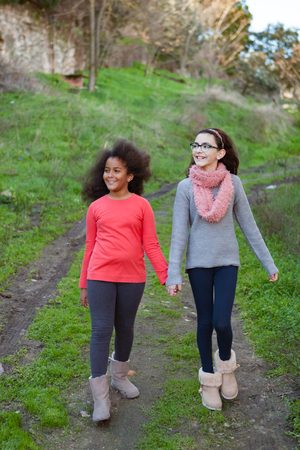 Two beautiful girls taking a walk by a green fieldの写真素材
