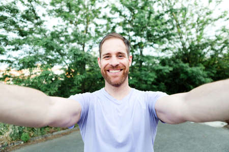 Casual guy in a park taking a photo with his mobileの写真素材