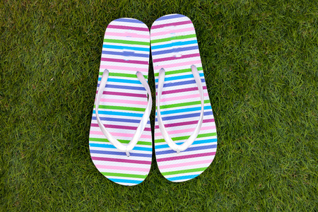 Flip-flops on the green grass of the poolの写真素材