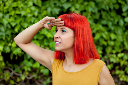 Red haired woman looking at the side in a parkの写真素材