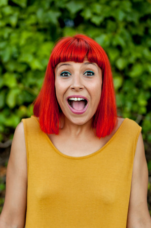 Surprised red haired woman in a park wearing yellow dressの写真素材