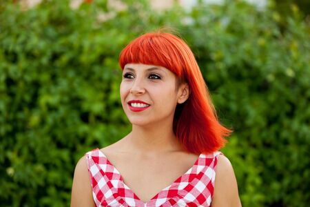 Red haired woman with red checkered dress relaxed in a parkの写真素材