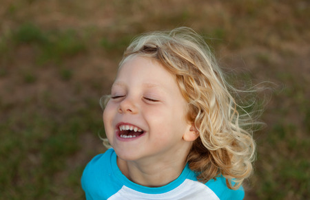 Small child with long blond hair enjoying of a sunny dayの写真素材