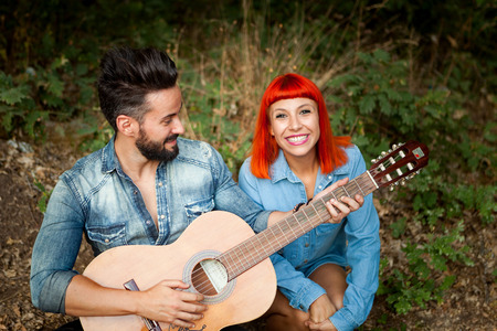 Young couple having fun with guitar in the park. Happy moments