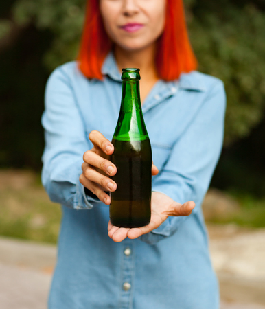 Redhead woman in the countryside toasting with a green bottle in the countrysideの写真素材