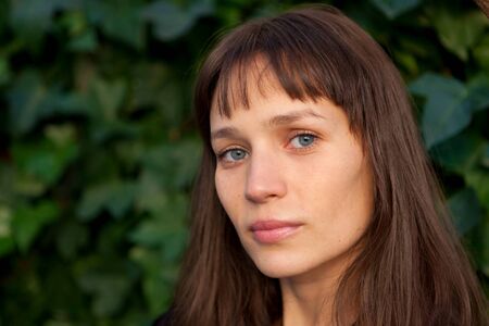 Beautiful woman with blue eyes and brown hair in the parkの写真素材