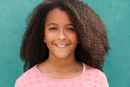 Cute African American girl smiling with afro hair on a green background