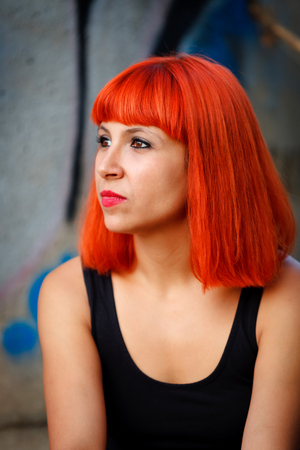 Attractive girl with red hair over a painted wall の写真素材