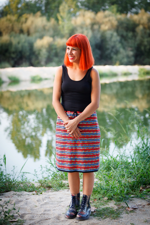 Beautiful redhead woman with a beautiful skirt relaxed outsideの写真素材