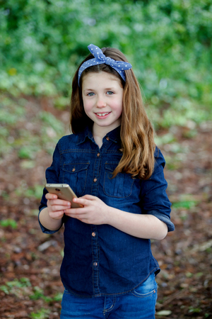 Happy girl with ten years old holding a phone in a parkの写真素材