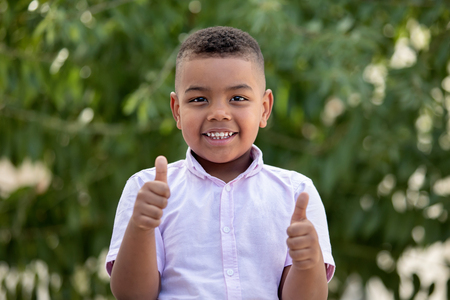 Latin child saying Ok in a gardenの写真素材