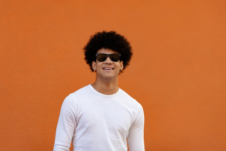 Handsome guy wiht sunglasses and a orange wall of backgroundの写真素材