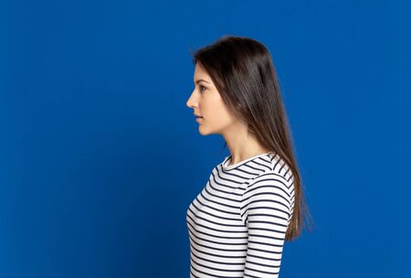 Brunette young woman wearing a striped T-shirt on a blue backgroundの写真素材