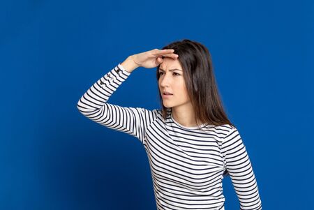 Brunette young woman wearing a striped T-shirt on a blue backgroundの写真素材