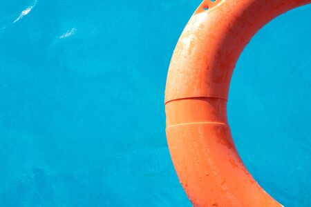 Orange lifebuoy floating on the surface of blue water in a poolの写真素材