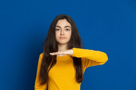 Brunette young girl wearing yellow jersey on a blue backgroundの写真素材