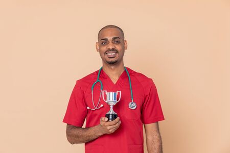 African doctor with a silvered trophy on a yellow background
