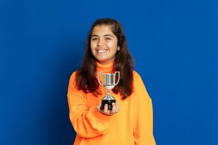 Adorable preteen girl with yellow jersey on a blue backgroundの写真素材