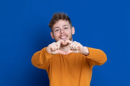 Attractive young guy with a yellow T-shirt on a blue background