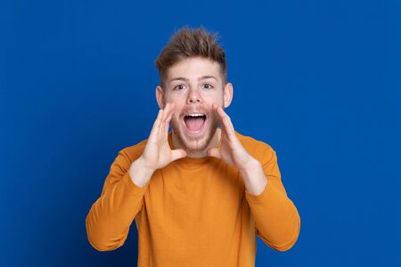 Attractive young guy with a yellow T-shirt on a blue backgroundの写真素材