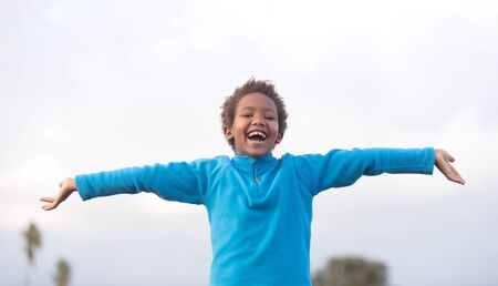 Happy african child with blue jersey opening his armsの写真素材