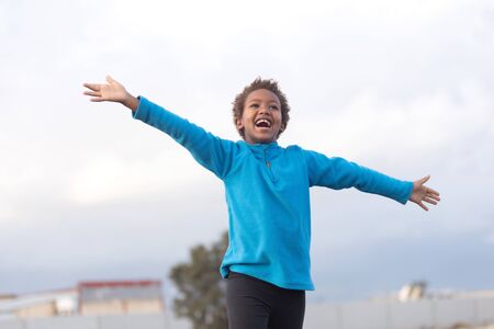 Happy african child with blue jersey opening his armsの写真素材