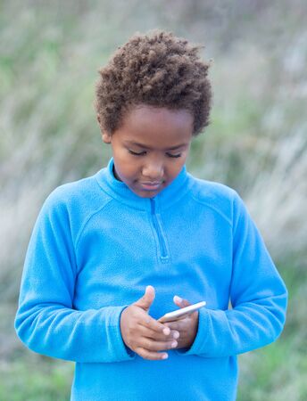 Adorable african child with a mobile phone outsideの写真素材