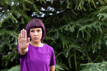 Angry woman with in purple showing the hand palm saying STOP isolated on a white background