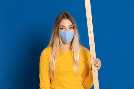 Blonde girl wearing a face mask on a blue background