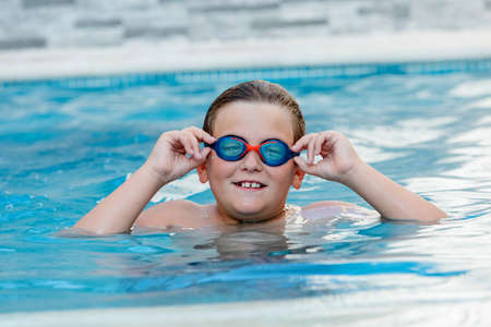 Beautiful blond child in the swimming pool on the summer