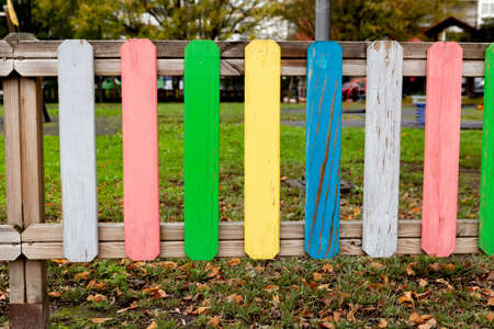 Rainbow wooden fence on kid playground at autumn