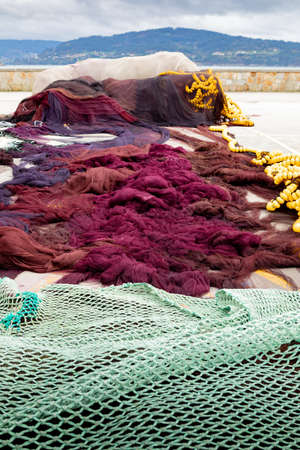 Fishing nets piled up in a small coastal harborの写真素材