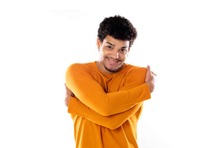 Cute african american man with afro hairstyle wearing an orange T-shirt isolated on a white...