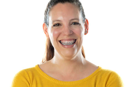 Adult woman in braces wearing a yellow jersey isolated on a white background