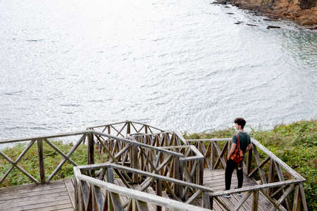 Guy with a leather backpack close to the coastの写真素材