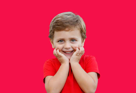 Cute surprised baby with blue eyes isolated on a red backgroundの写真素材