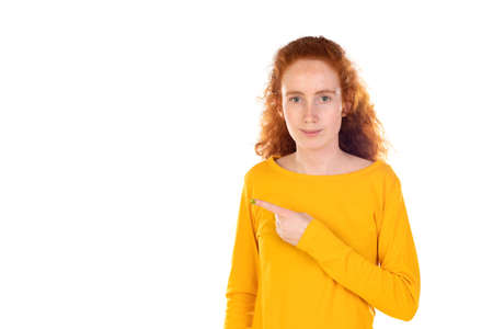 Young pretty woman smiling confidently pointing to something, positive, relaxed, satisfied attitude against white backgroundの写真素材