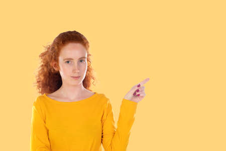 Young pretty woman smiling confidently pointing to something, positive, relaxed, satisfied attitude...