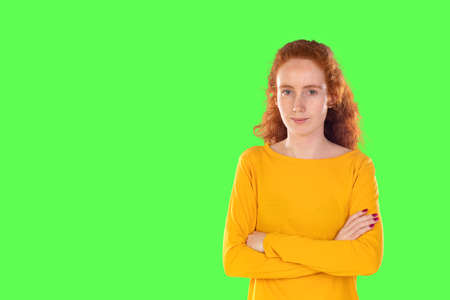 Close-up cheerful attractive redhead girl long healthy hair smiling camera isolated on a green backgroundの写真素材