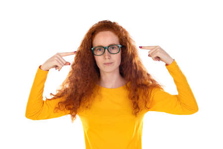 Head shot studio portrait young serious red-headed woman wearing blue t-shirt glasses looking at...