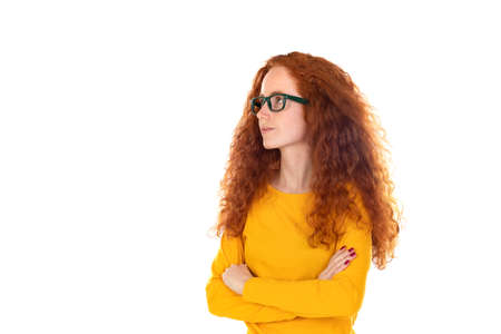 Head shot studio portrait young serious red-headed woman wearing blue t-shirt glasses looking at...