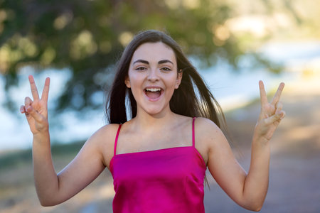 Winner girl spending a day in a park doing the victory sign with her fingersの写真素材