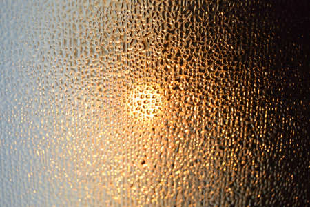 Rainy abstract golden color frame and water droplet pattern on glass window. Liquid textured bubbles...